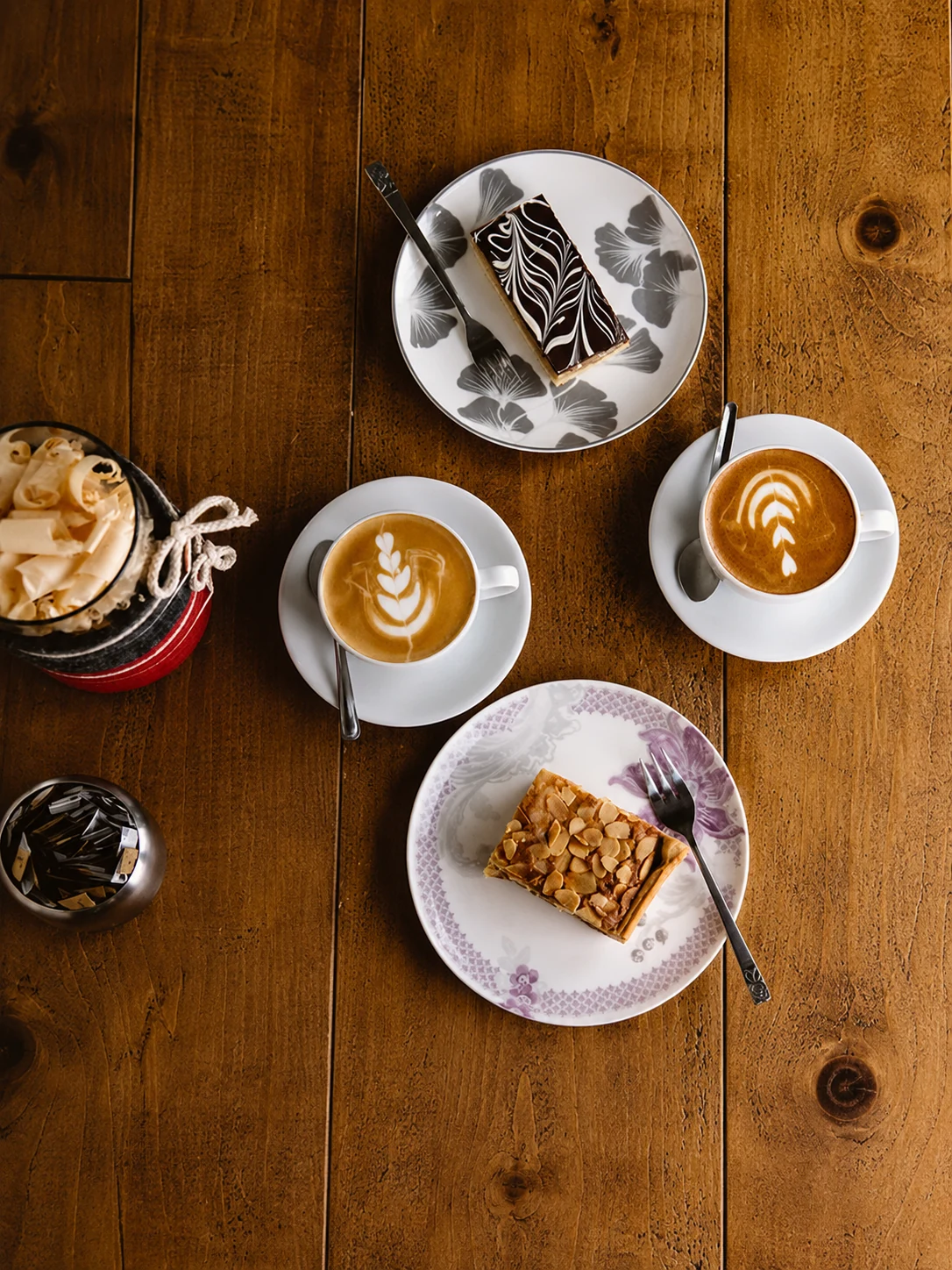 Coffee cups and slices of cake arranged on a wooden table